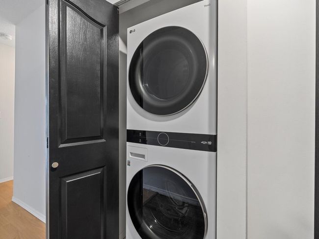 Laundry area featuring stacked washer / dryer, baseboards, laundry area, and wood finished floors | Image 18
