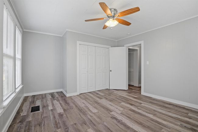 Unfurnished bedroom featuring wood finished floors, ornamental molding, a closet, and ceiling fan | Image 11