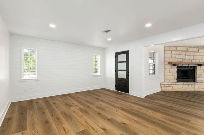 Bright and inviting living area featuring elegant flooring, abundant natural light, and a charming stone fireplace for cozy gatherings. | Image 16
