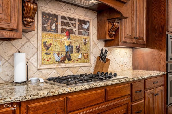 Kitchen featuring stainless steel appliances, backsplash, light stone counters, and brown cabinets | Image 14