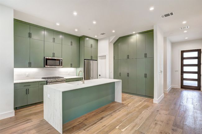 Kitchen featuring green cabinets, premium appliances, backsplash, light countertops, and recessed lighting | Image 23