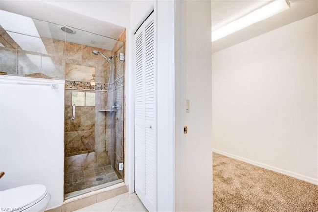 Full bath with baseboards, a stall shower, toilet, and a closet | Image 12