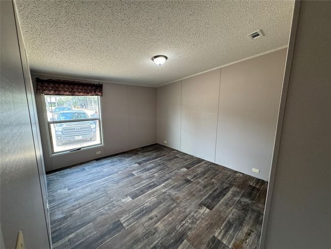 Unfurnished room with dark wood-style flooring, a textured ceiling, and visible vents | Image 14