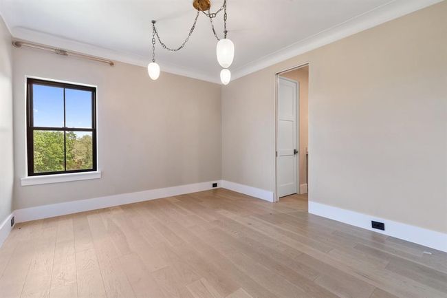 The third bedroom features a beautiful chandelier and neutral paint. The passage on the right leads to a walk in closet and full bathroom. | Image 29