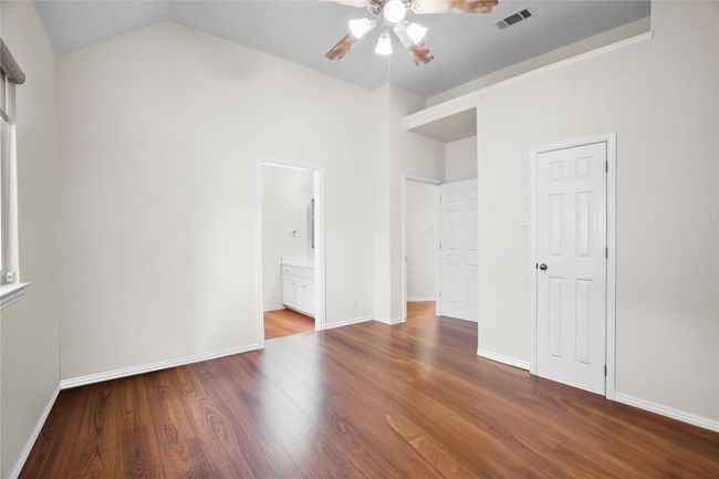 Unfurnished bedroom with wood finished floors, vaulted ceiling, ensuite bath, and ceiling fan | Image 27