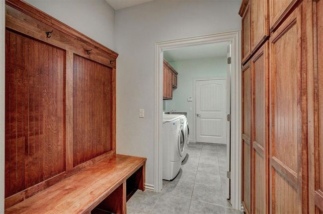 Laundry room featuring washing machine and dryer, cabinet space, and light tile patterned flooring | Image 38