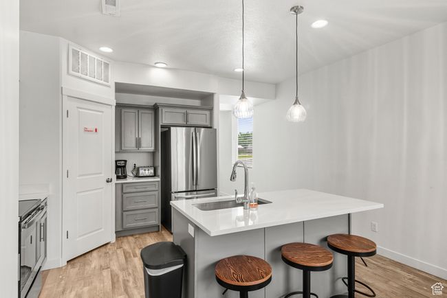 Kitchen with visible vents, light wood finished floors, a sink, gray cabinetry, and appliances with stainless steel finishes | Image 8