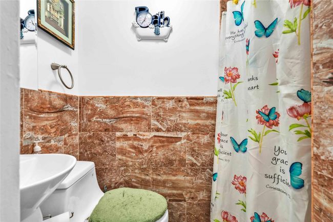 Full bath with toilet, tile walls, a sink, and a shower with shower curtain | Image 21