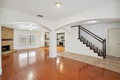 Unfurnished living room featuring a textured ceiling, ceiling fan, hardwood / wood-style floors, and a fireplace | Image 3