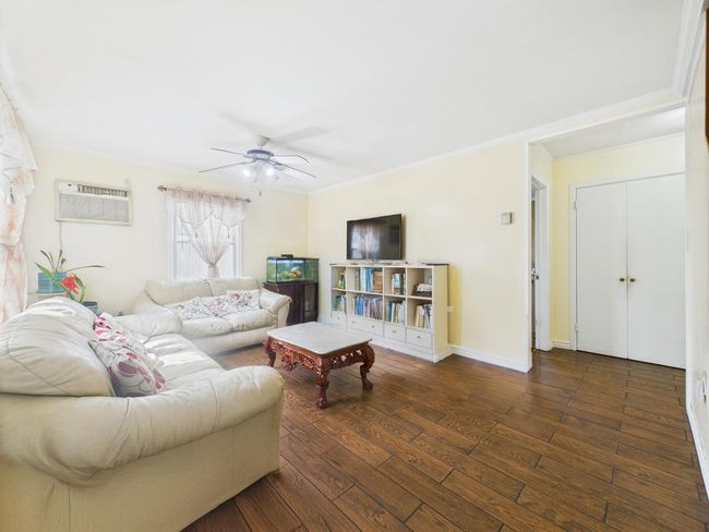 Living room with a wall mounted AC, ceiling fan, hardwood / wood-style floors, and crown molding | Image 4