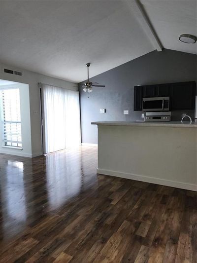 Unfurnished living room with ceiling fan, dark hardwood / wood-style flooring, and vaulted ceiling with beams | Image 3