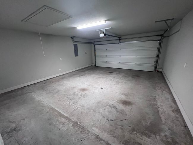 Garage featuring a garage door opener, baseboards, and electric panel | Image 32