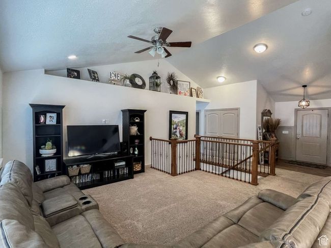 Carpeted living area featuring lofted ceiling and ceiling fan | Image 17