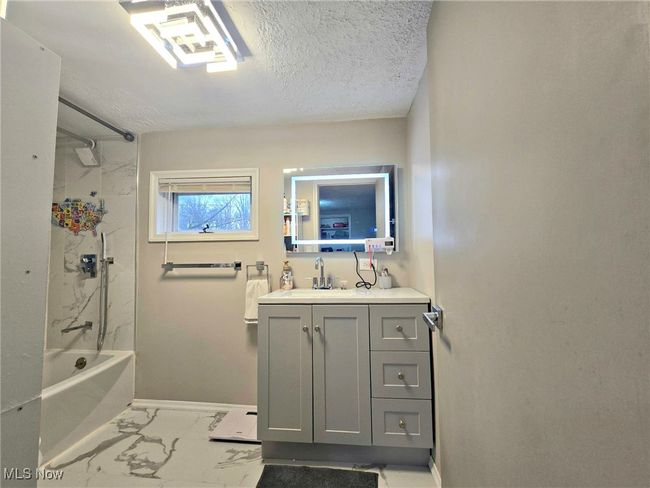Bathroom featuring baseboards, shower / washtub combination, vanity, marble finish floor, and a textured ceiling | Image 41