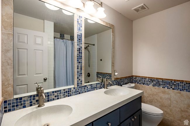 Full bathroom featuring double vanity, tile patterned floors, a stall shower, and a sink | Image 21