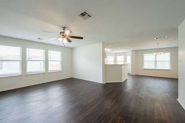 Unfurnished room with a chandelier, dark wood-style flooring, a ceiling fan, and baseboards | Image 7
