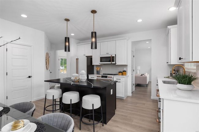 Kitchen featuring light wood-type flooring, a center island, sink, white cabinets, and appliances with stainless steel finishes | Image 9