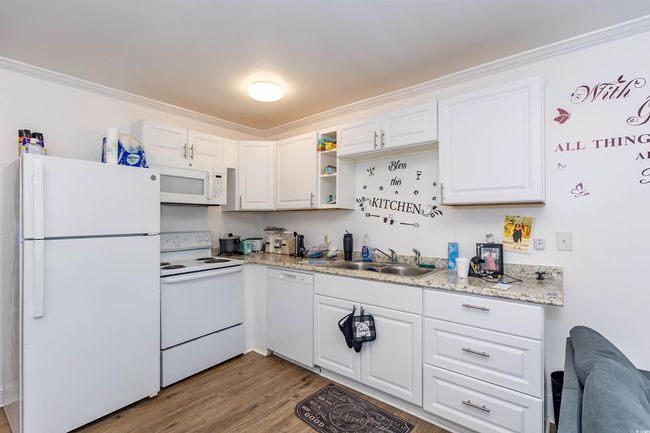 Kitchen with a sink, white cabinets, light wood-type flooring, and white appliances | Image 18