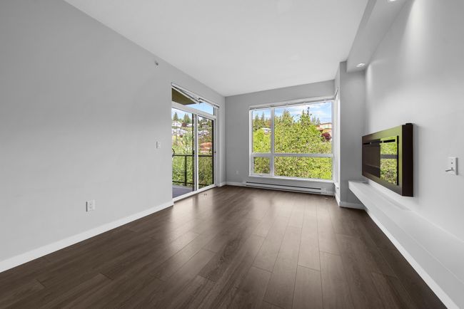 Unfurnished living room with a baseboard heating unit, dark wood finished floors, and baseboards | Image 21