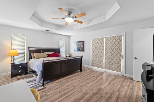 Bedroom with baseboards, light wood-style flooring, visible vents, and a raised ceiling | Image 16