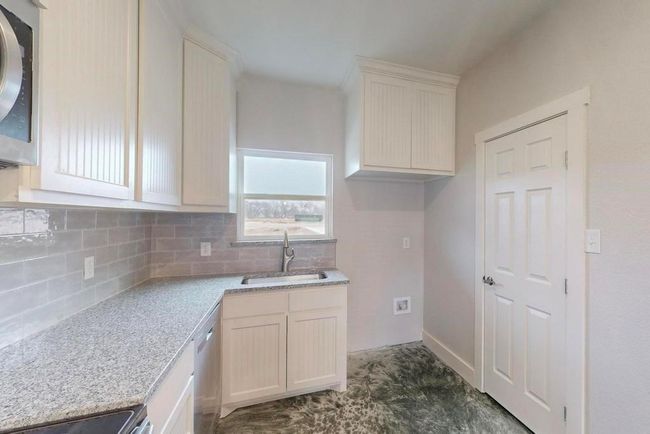 Kitchen featuring range, light stone countertops, dishwasher, a sink, and decorative backsplash | Image 9