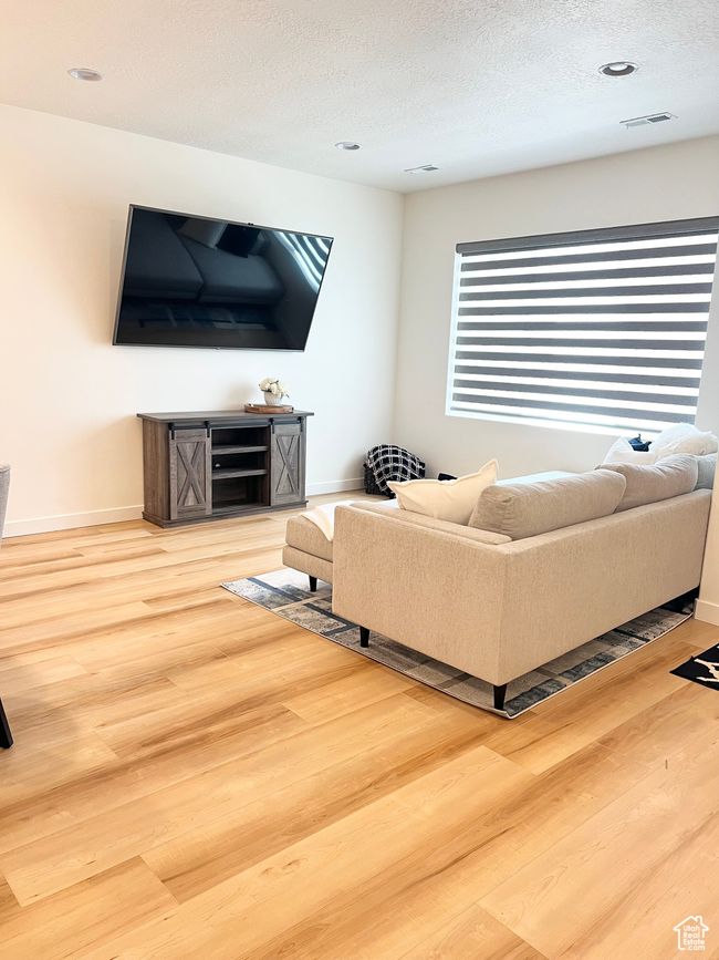 Living area featuring wood finished floors, a textured ceiling, and recessed lighting | Image 8
