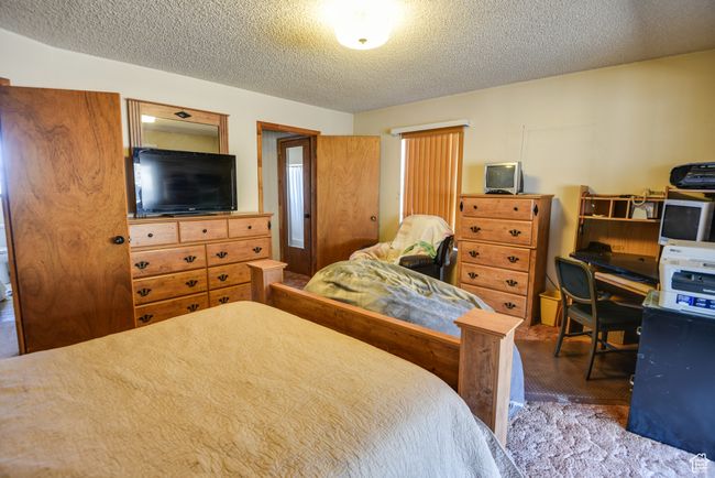 Carpeted bedroom with a textured ceiling | Image 17