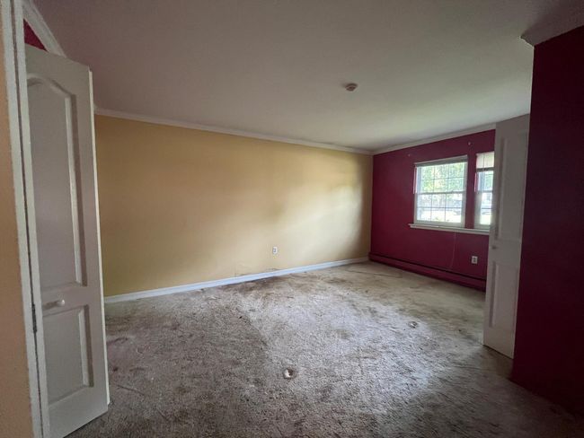 Unfurnished room featuring crown molding, carpet floors, baseboards, and baseboard heating | Image 9