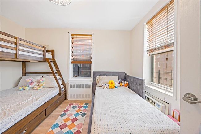 Bedroom with radiator heating unit, light wood-type flooring, and a wall mounted AC | Image 14