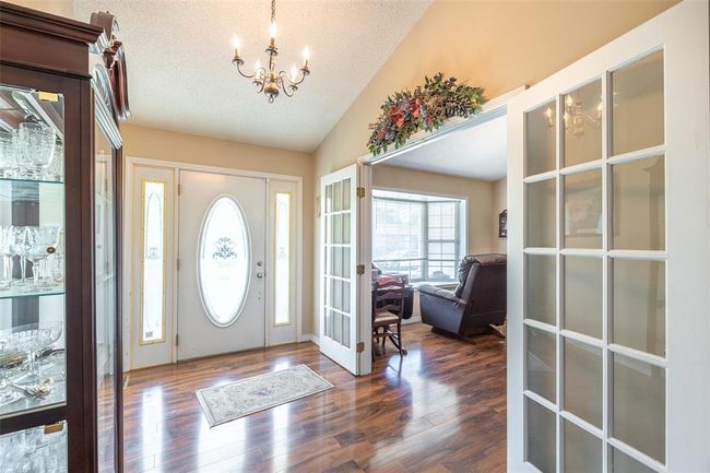 Foyer entrance with a chandelier, a textured ceiling, dark wood-style flooring, vaulted ceiling, and french doors | Image 10