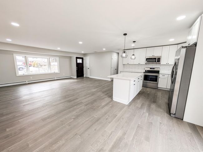 Kitchen featuring decorative backsplash, open floor plan, baseboard heating, stainless steel appliances, and light wood-style floors | Image 8