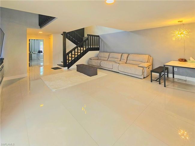 Tiled living room featuring a notable chandelier, baseboards, recessed lighting, and stairs | Image 12