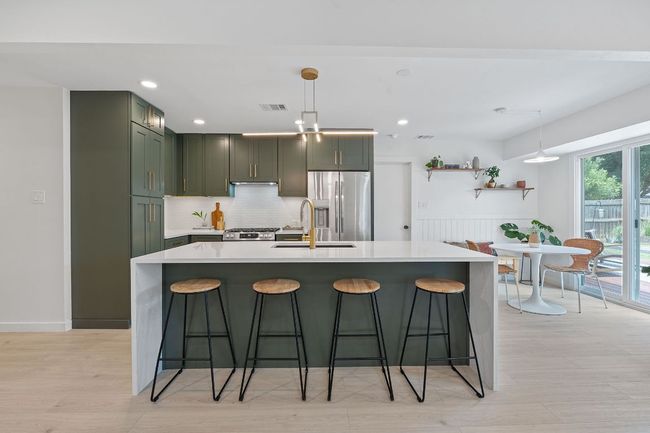 Kitchen featuring appliances with stainless steel finishes, light countertops, a breakfast bar, recessed lighting, and wainscoting | Image 14