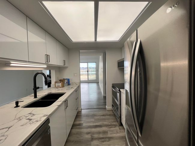 Kitchen featuring appliances with stainless steel finishes, white cabinets, dark wood-type flooring, light stone counters, and modern cabinets | Image 11