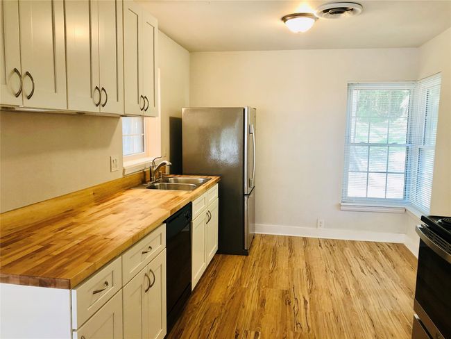 Kitchen featuring wood counters, wood finished floors, dishwasher, stove, and freestanding refrigerator | Image 9