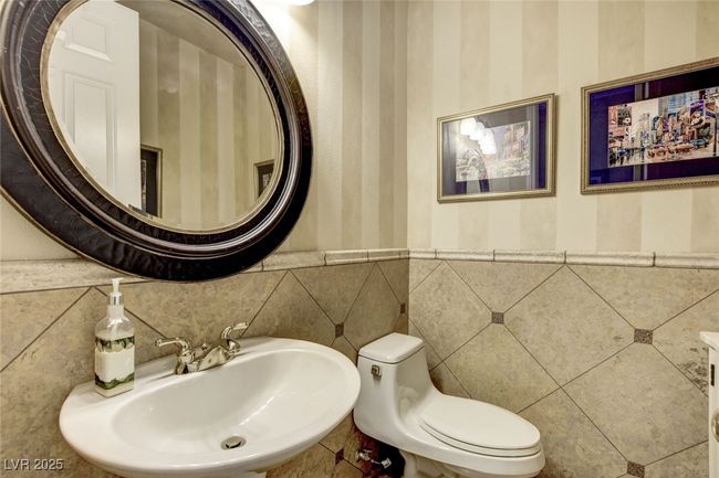 Bathroom with toilet, a wainscoted wall, a sink, and tile walls | Image 23