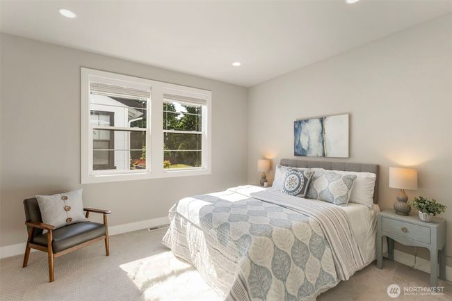 This upstairs spare bedroom is bright and welcoming, with large windows that invite in natural light and views of the landscaped yard. Neutral tones and plush carpeting create a cozy, restful space—ideal for guests, family, or a stylish home office. | Image 32