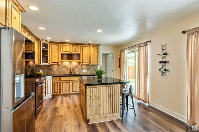 Kitchen featuring appliances with stainless steel finishes, dark countertops, dark wood-style floors, a kitchen island, and recessed lighting | Image 16