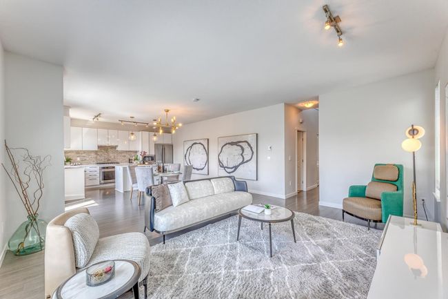 Living room with wood finished floors, rail lighting, and a chandelier | Image 6