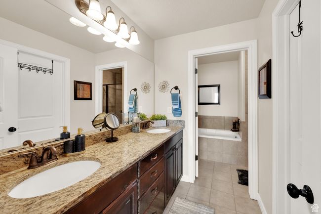 Bathroom featuring tile patterned flooring, double vanity, a garden tub, and a tile shower | Image 15