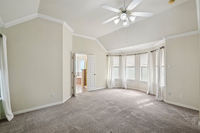 Unfurnished bedroom featuring lofted ceiling, crown molding, carpet, and a ceiling fan | Image 11