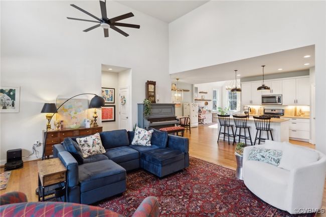 Living area featuring recessed lighting, ceiling fan with notable chandelier, light wood-style floors, and a towering ceiling | Image 7