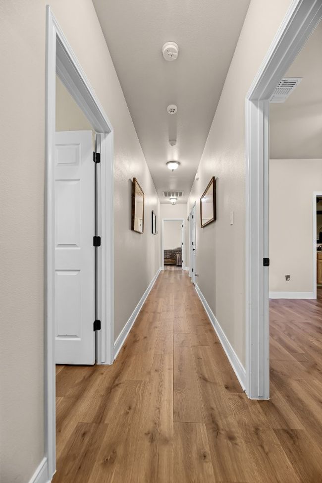 Hall with wood finished floors, baseboards, and visible vents | Image 20
