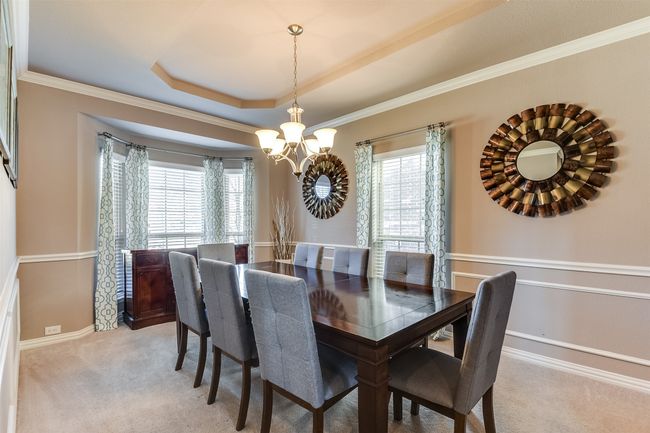 Carpeted dining space with a tray ceiling, ornamental molding, and an inviting chandelier | Image 7