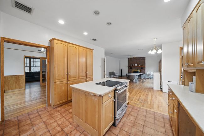 Kitchen featuring a center island, stainless steel electric stove, a chandelier, light countertops, and visible vents | Image 16