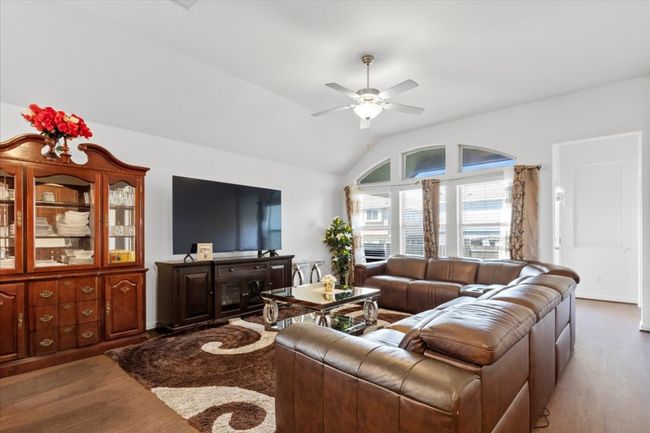 Living area featuring vaulted ceiling, wood finished floors, and ceiling fan | Image 8