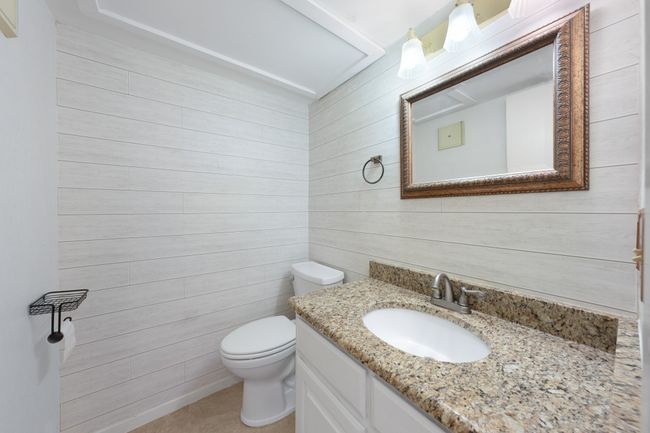 Updated downstairs half bathroom with decorative wall treatment and granite counters. | Image 12