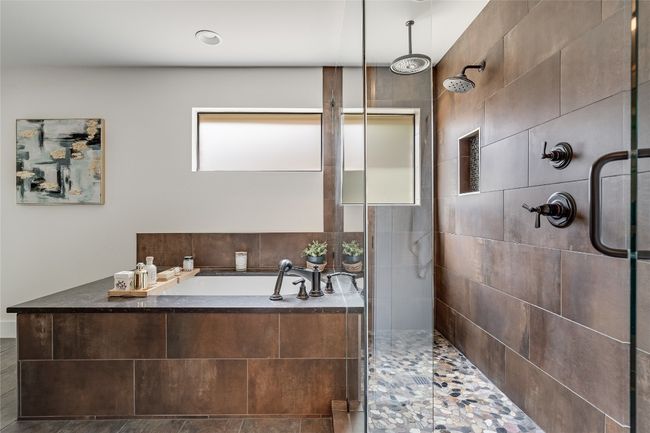 The walk-in shower is surrounded in frameless glass with tile backsplash and a gorgeous pebble base and boasts a relaxing overhead rain shower feature. | Image 26