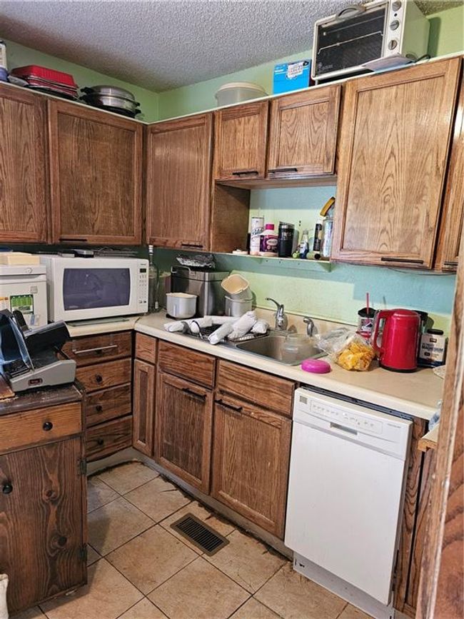 Kitchen featuring visible vents, light tile patterned flooring, a textured ceiling, and dishwashing machine | Image 12
