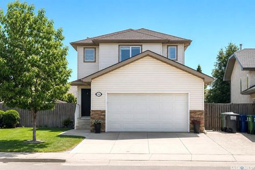 Two-story home featuring light-colored siding, a prominent two-car garage, and a covered entryway | Card Image
